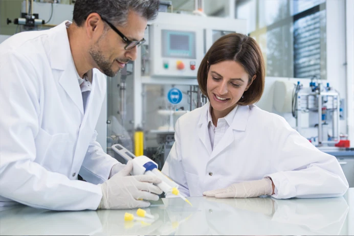 Man and a woman in lab coats with a tool