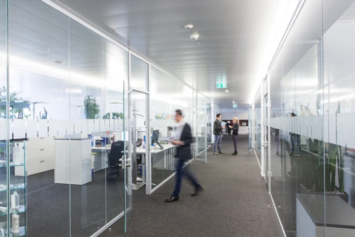 Photo of an office with glass walls and a blury person